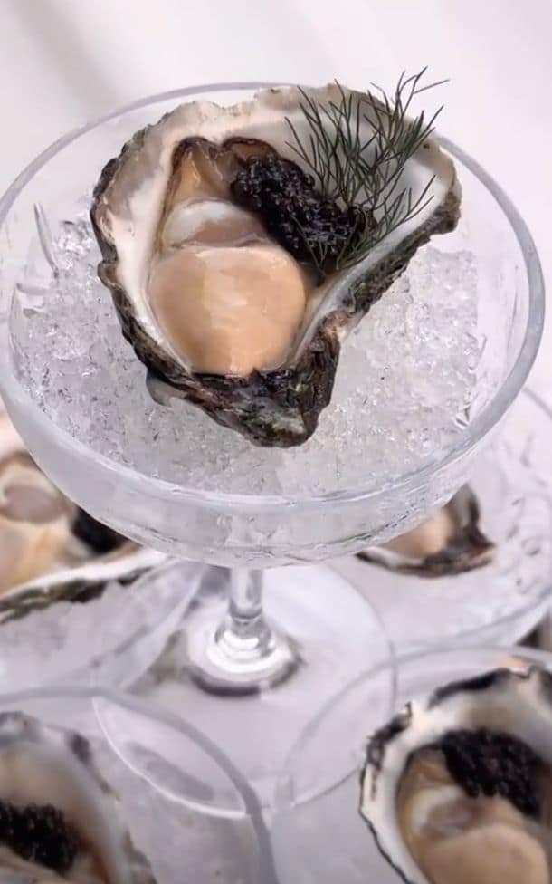 Ostra fresca coroada com caviar e endro, servida em taça sobre gelo.